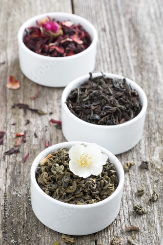 Assorted dry herbal teas in white bowls, vertical