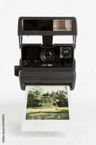 Old-fashioned instant camera with finished photoshot