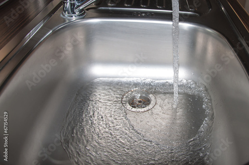 Stainless steel sink plug hole close up with water photo