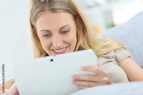 Blond woman at home using digital tablet