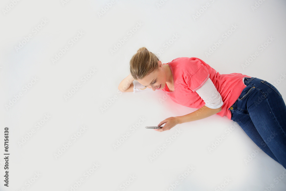 Young woman laying on floor with smartphone, isolated Young woman laying on floor with smartphone, isolated