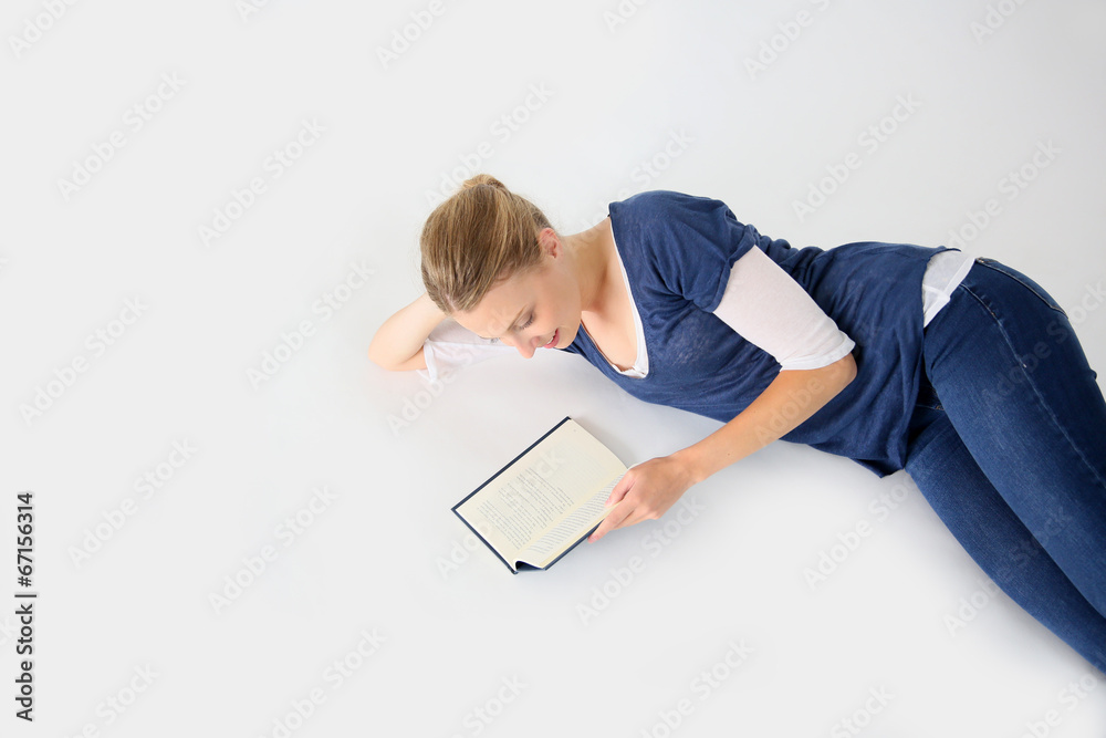 Young woman laying on floor reading a book, isolated Young woman laying on floor reading a book, isolated
