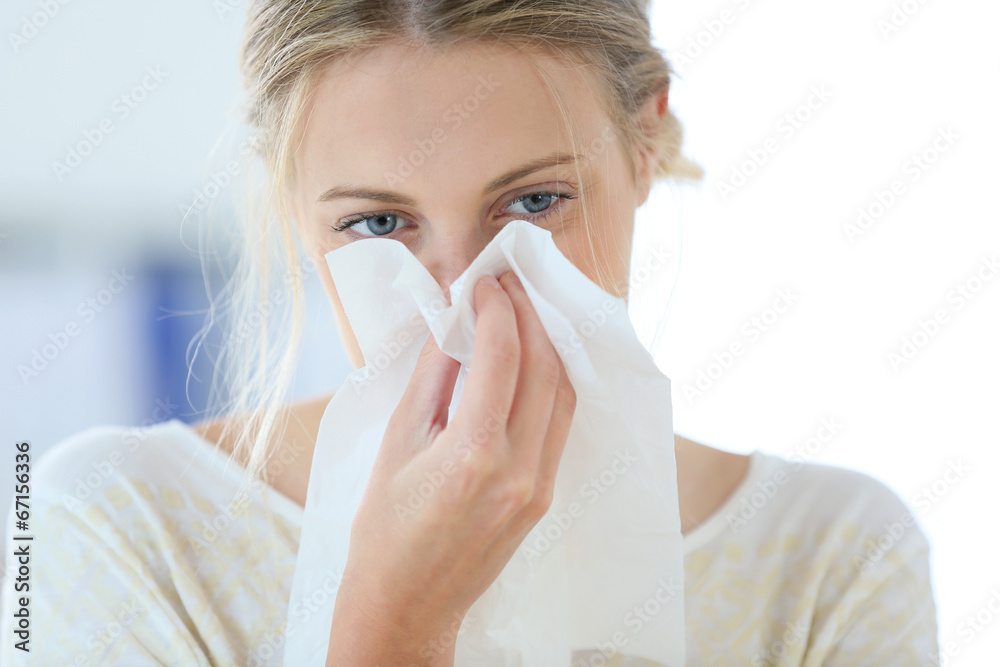Young woman with cold blowing her runny nose Young woman with cold blowing her runny nose