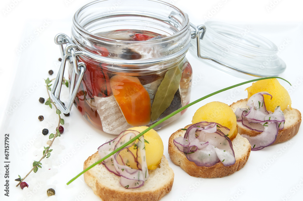 pickled herring in a glass jar with potato canapes pickled herring in a glass jar with potato canapes