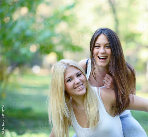 Close up portrait of two happy girls hugging outdoors