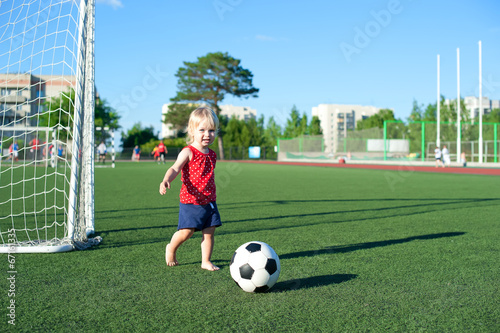 Little girl football fan on the green grass field with ball © ssnegireva