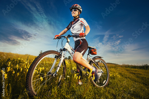 Woman is riding bicycle outside in the field