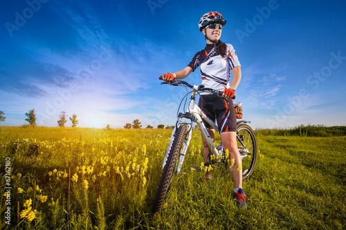 Woman is riding bicycle outside in the field