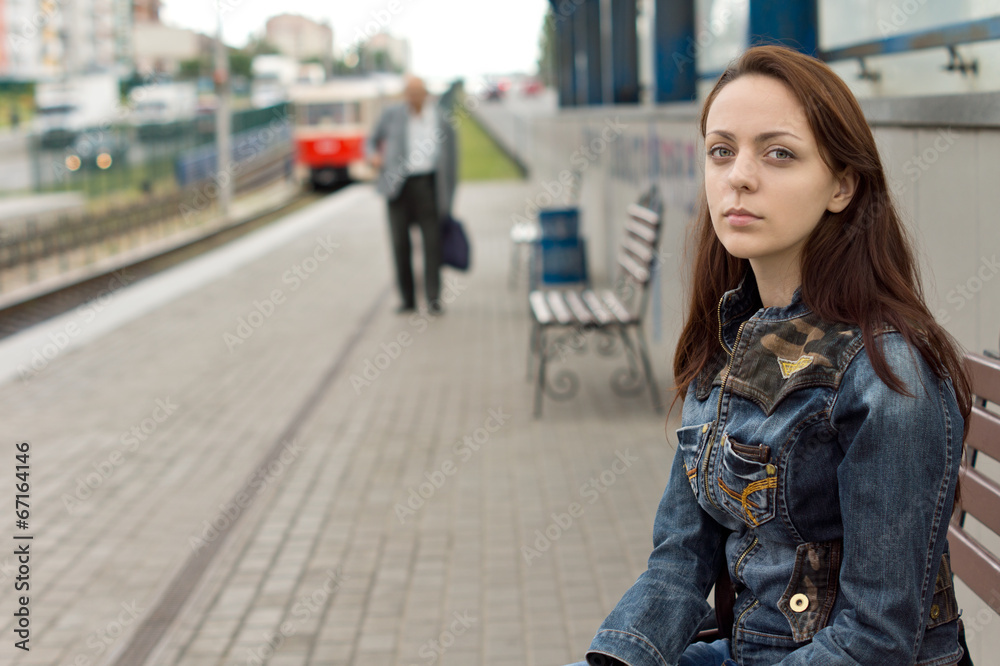 Lonely girl waiting in an urban railway station