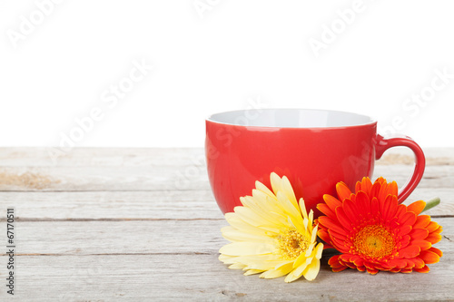 Cup of coffee and gerbera on wooden table