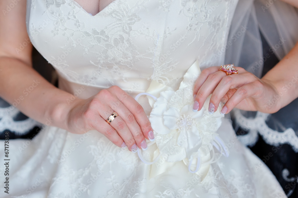 bride adjusts white bow on her dress