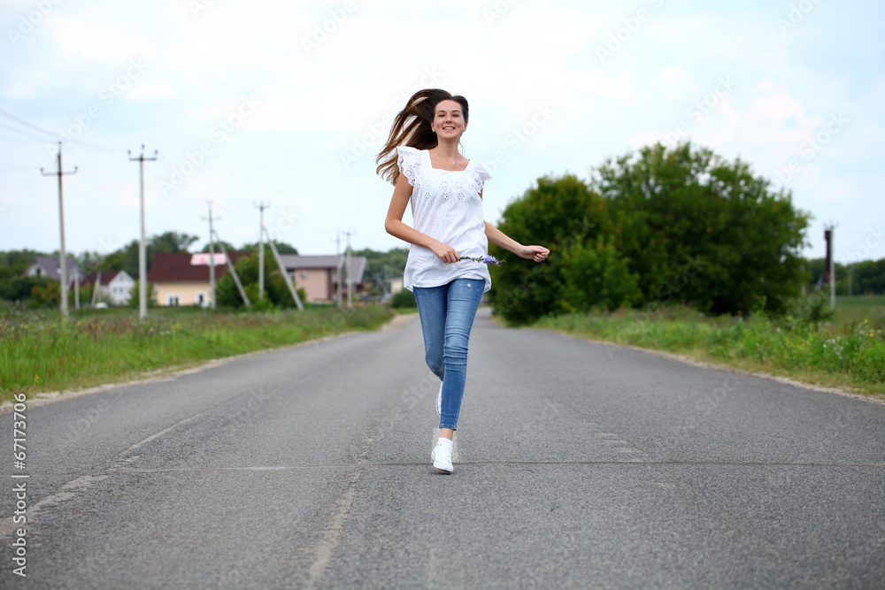 Young woman running along a country road
