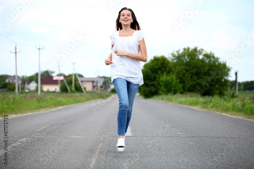Young woman running along a country road