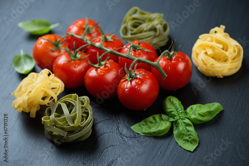 Branch of red tomatoes, green basil and tagliatelle, studio shot