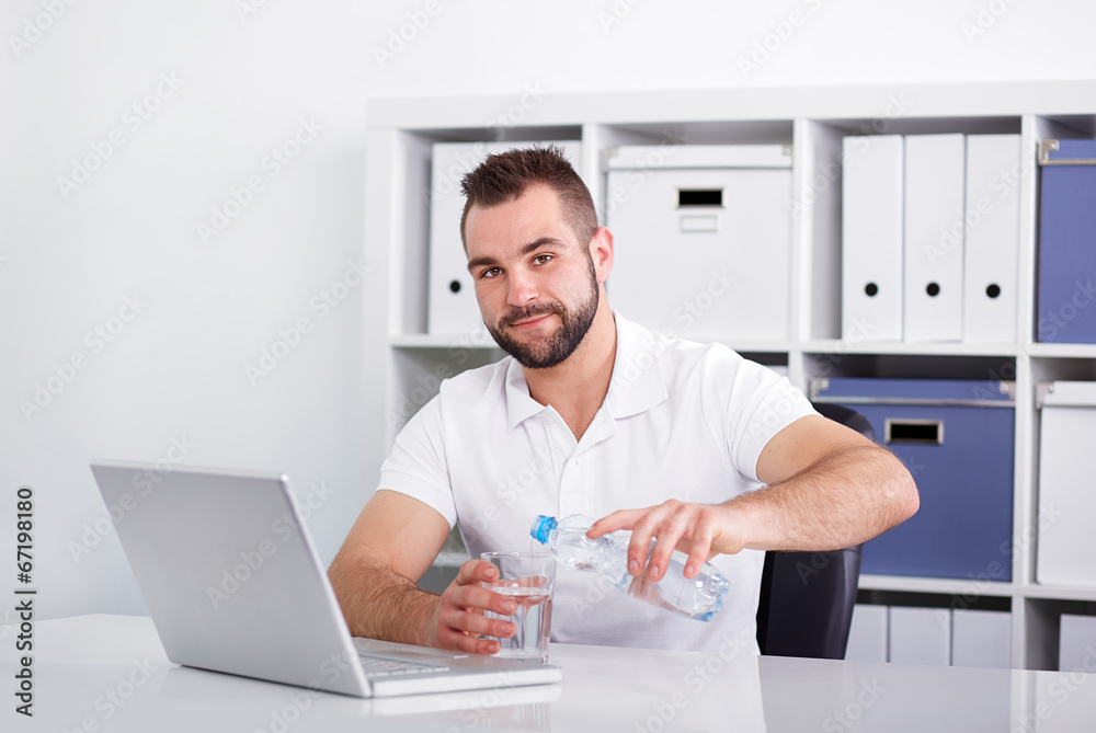 Handsome young man pouring water into a glass