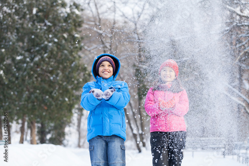 boy and girl throwing snow into air. photo