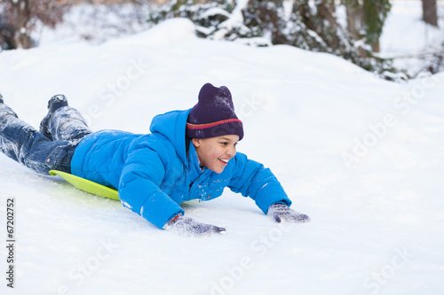boy lying on sledges and sliding down hill.