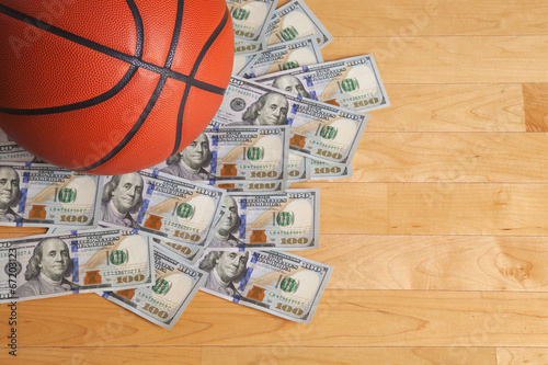 Basketball on pile of one hundred dollar bills