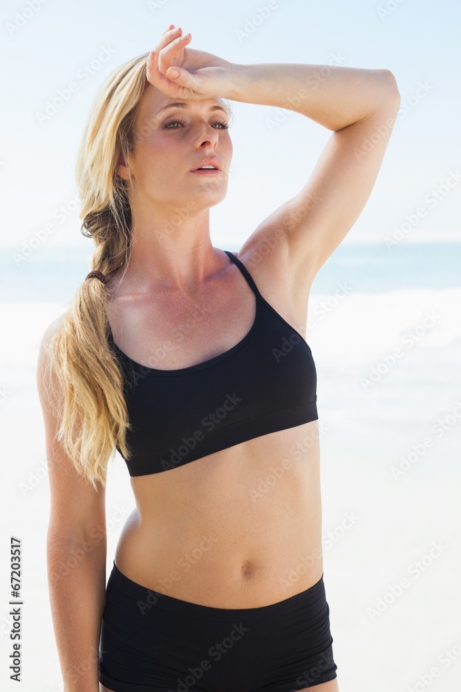 Fit blonde wiping her forehead on the beach Fit blonde wiping her forehead on the beach