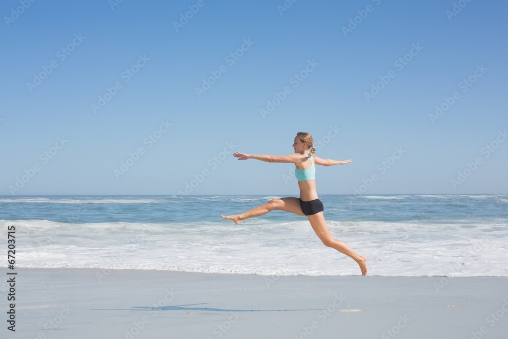 Fit woman jumping gracefully on the beach Fit woman jumping gracefully on the beach