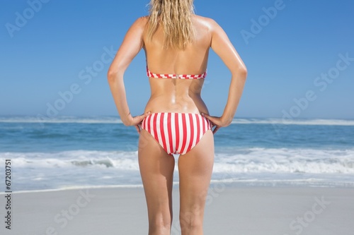 Mid section rear view of fit woman in striped bikini at beach