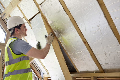 Builder Fitting Insulation Into Roof Of New Home photo