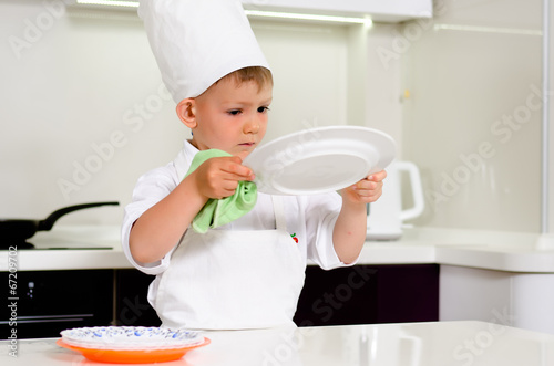 Cute young chef checking his dinner plates