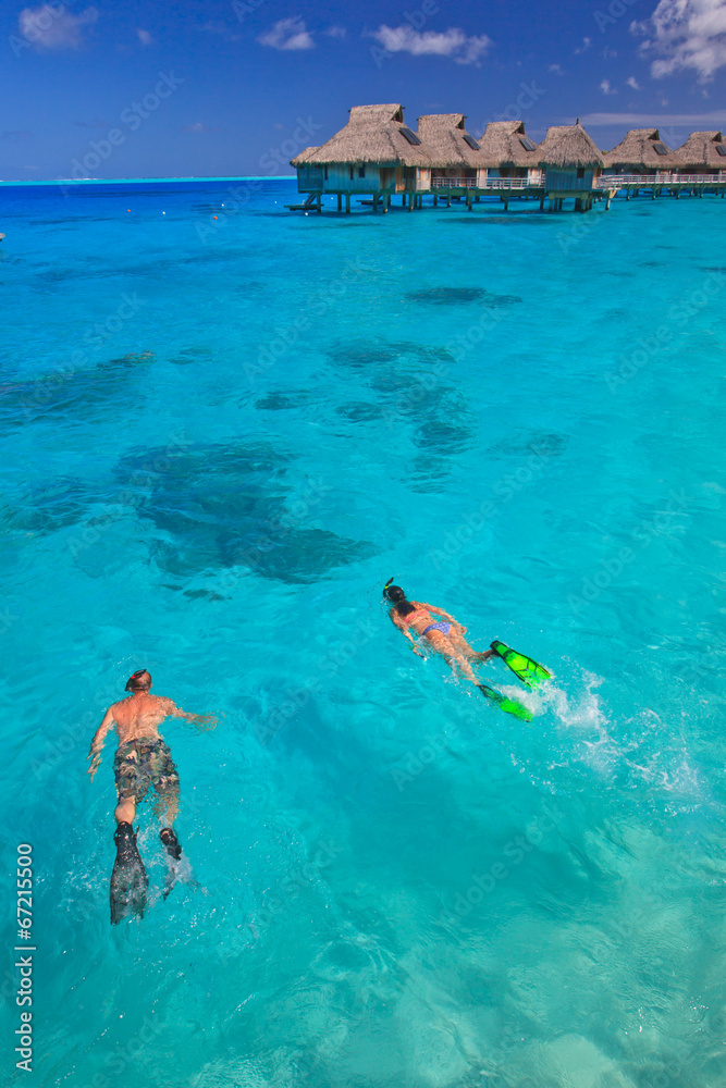 Couple snorkeling in the blue lagoon, Bora Bora, South Pacific