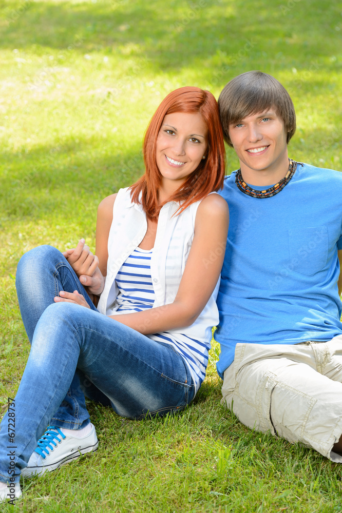 Teenage couple sitting on grass embracing summer Teenage couple sitting on grass embracing summer