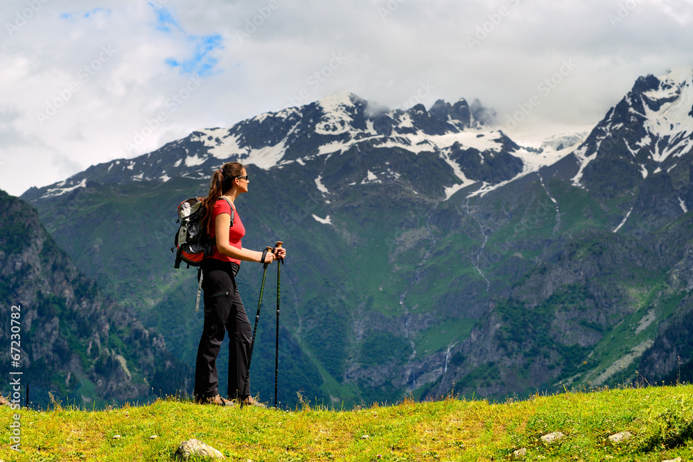 Young woman with backpack and trekking poles in mountains Young woman with backpack and trekking poles in mountains
