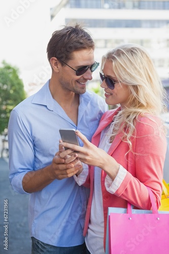 Stylish young couple looking at smartphone holding shopping bags © WavebreakMediaMicro