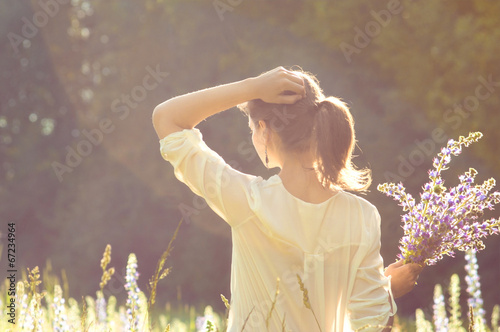summer background girl in a field with flowers in their hands in