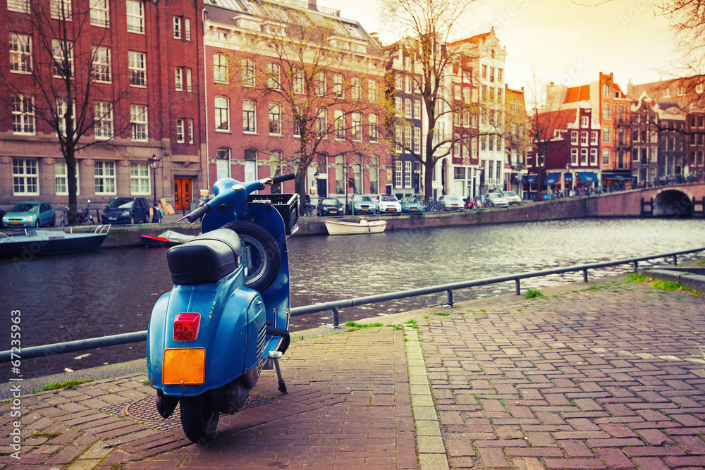 Fototapeta premium Blue scooter stands parked on the canal coast in Amsterdam. Inst