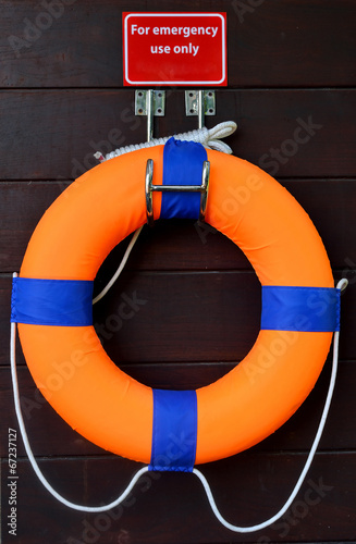 Red life buoy on a wooden wall