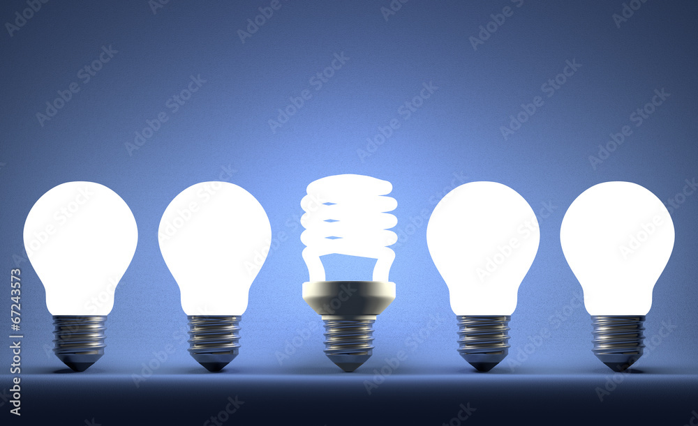 Glowing spiral light bulb in row of tungsten ones on blue Glowing spiral light bulb in row of tungsten ones on blue
