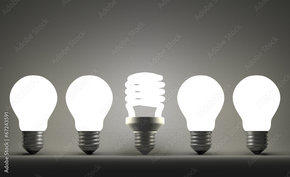 Glowing spiral light bulb in row of tungsten ones on gray Glowing spiral light bulb in row of tungsten ones on gray