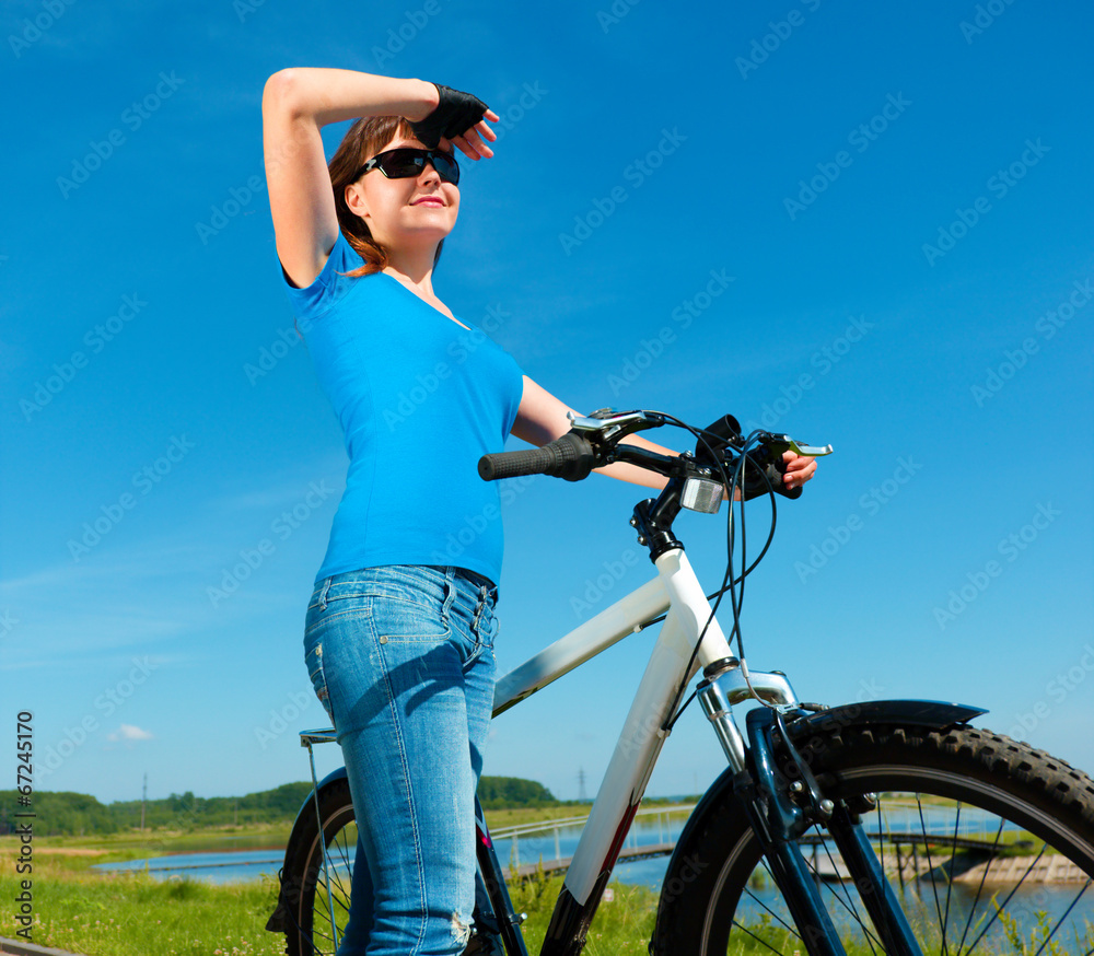 Young woman is standing in front of her bicycle Young woman is standing in front of her bicycle