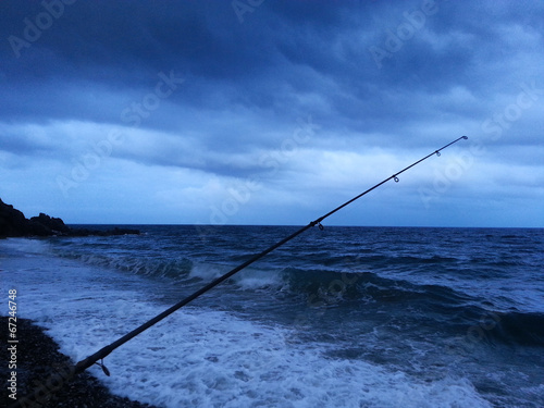 Pesca sulla riva del mare mentre arriva un temporale