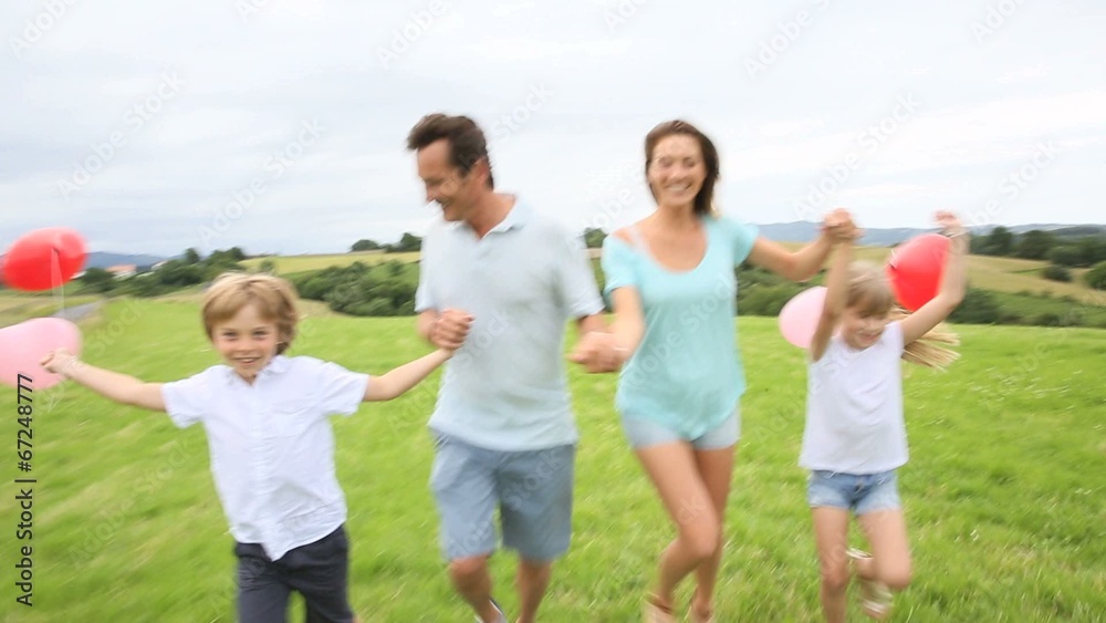 Family running in countryside, kids holding balloons Family running in countryside, kids holding balloons