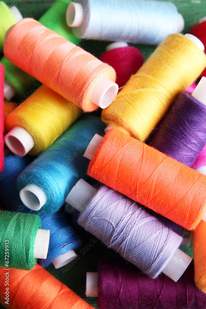 Multicolor sewing threads on wooden background Multicolor sewing threads on wooden background
