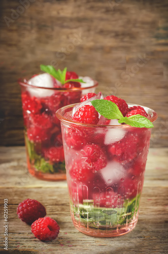 Summer juice with fresh raspberries mint and ice in a glass