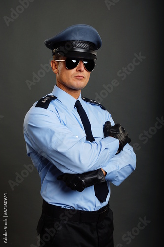 Policeman in uniform with sunglasses on gray background