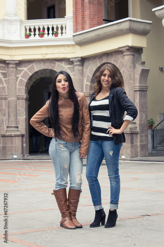 two casual hispanic girls posing with hand on hip