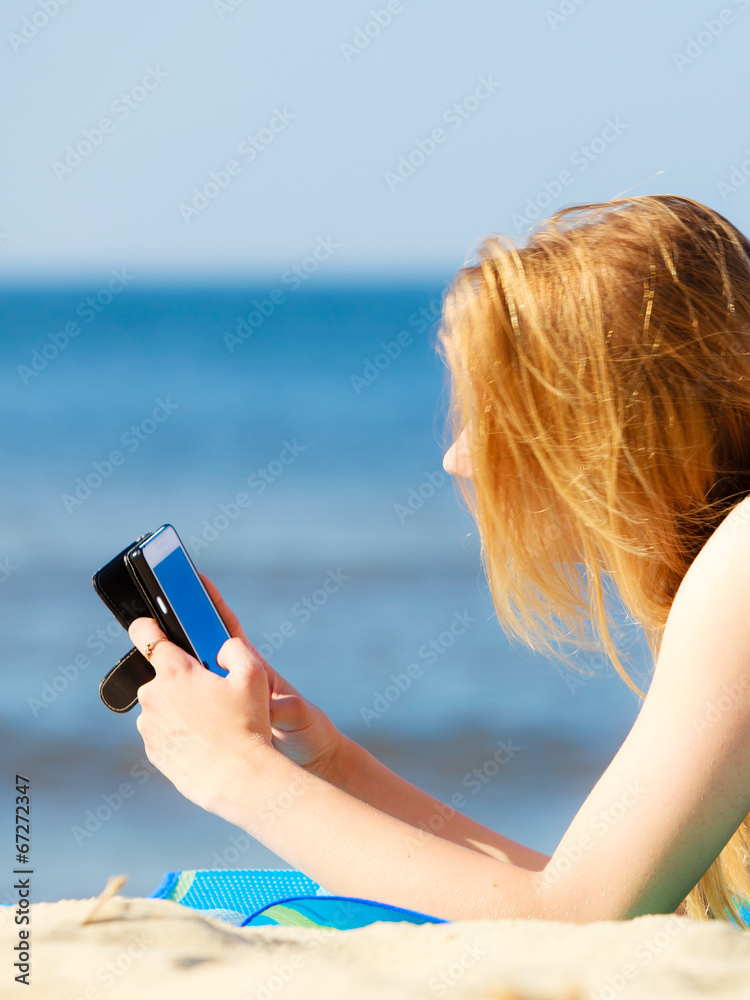 Summer vacation Girl with phone tanning on beach