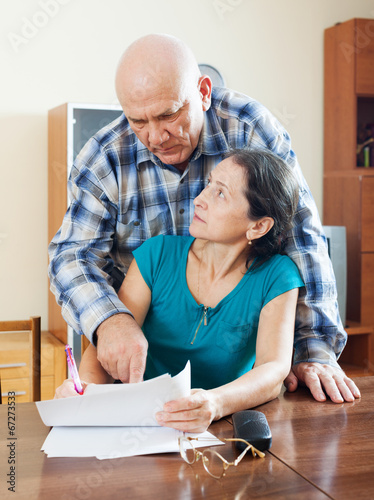  mature woman fills documents, man helping her