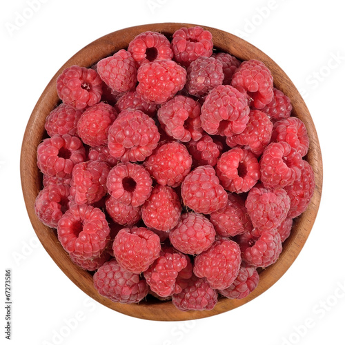 Red raspberries in a wooden bowl on a white