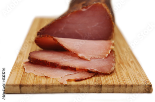 Sliced prosciutto on a wooden board isolated on white background