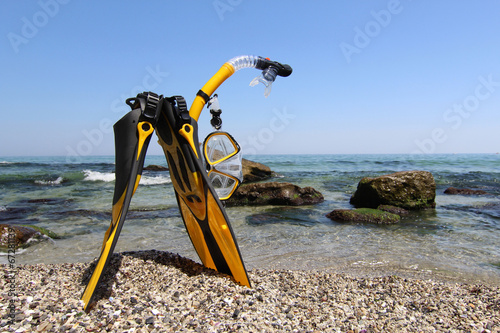Photography Flippers, mask and snorkel lying on sandy beach. Sea background