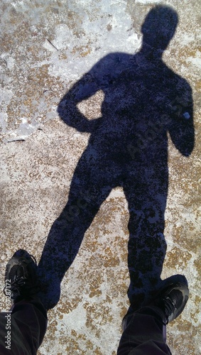 Male feet standing on concrete with shadow silhouette