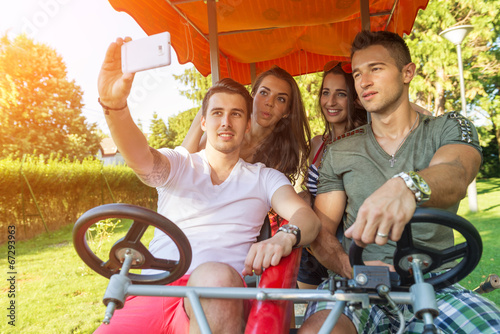 Photos Four young people in a four-wheeled bicycle, they do selfie